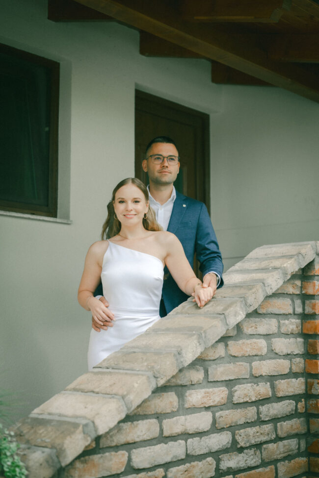 A menyasszony és a vőlegény egy téglalépcsőn pózolva az esküvői kreatív fotózásukon.