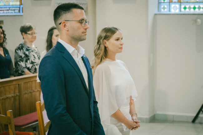 A pár figyelmesen áll az oltár előtt a templomi esküvői ceremónia alatt.