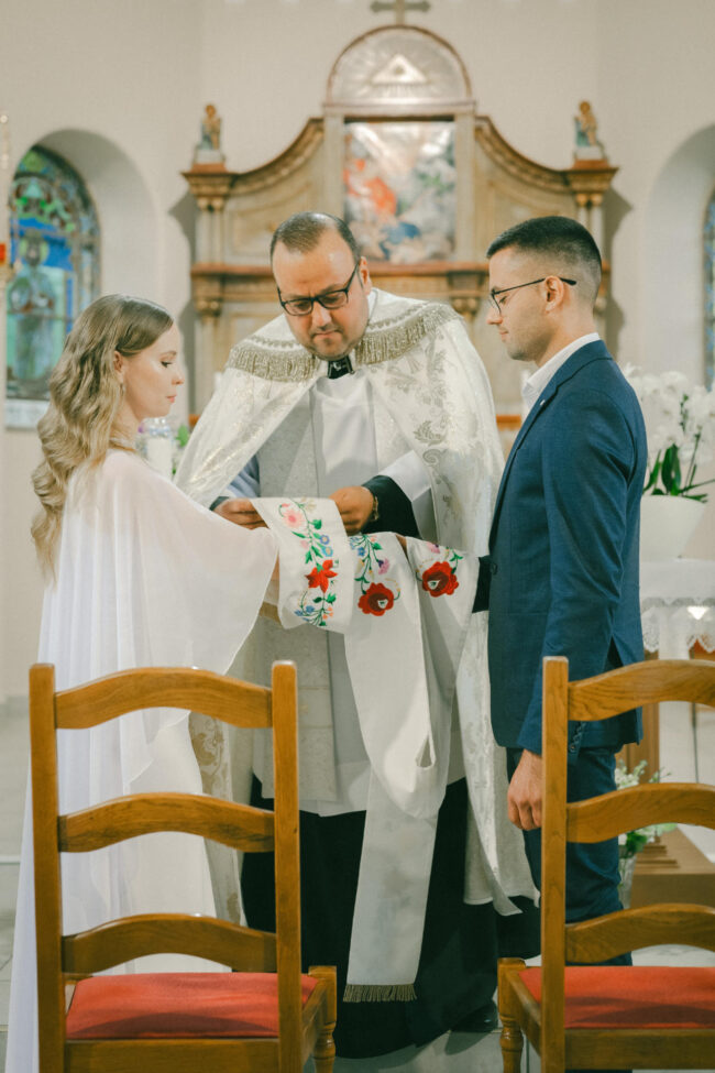 A pap áldást ad a fiatal párra a hagyományos templomi esküvői szertartáson.