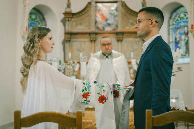 Ünnepélyes pillanat a templomi esküvőn az oltár előtt a stóla alatt.